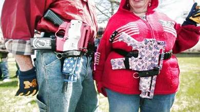 أميركيان يستعرضان أسلحتهما خلال تجمع للمدافعين عن الحق في حمل السلاح علنا، في رومولوس بولاية ميشيغن في 26 ابريل 2014 